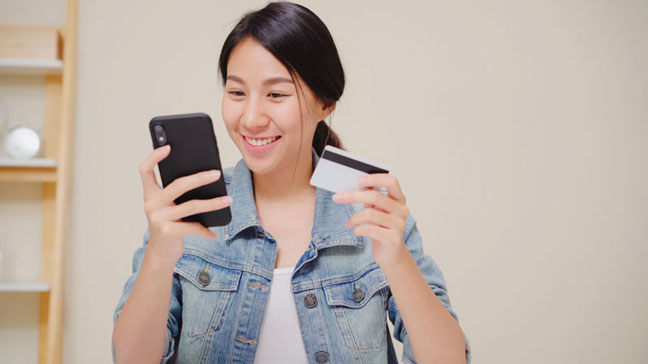 Young woman using smartphone to buy contact lenses from her eye doctor online